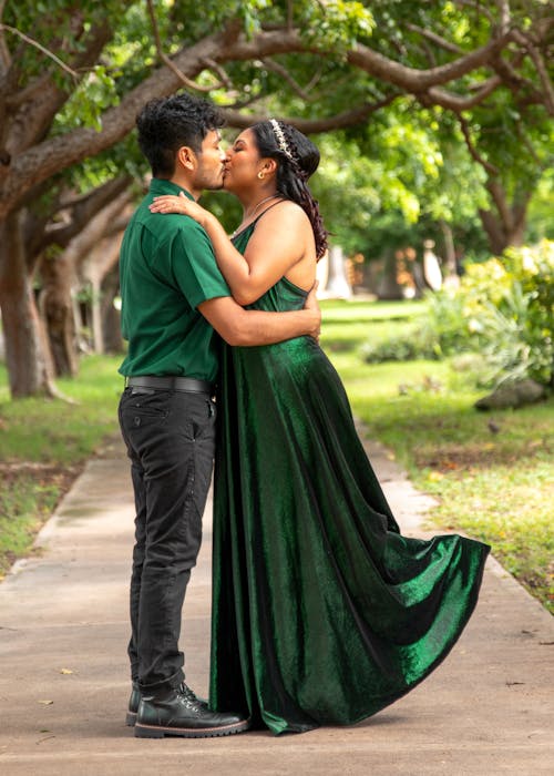Couple in Green Kissing on Path in Park
