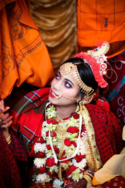 A beautiful Indian bride adorned in traditional attire with a maang tikka and nath.