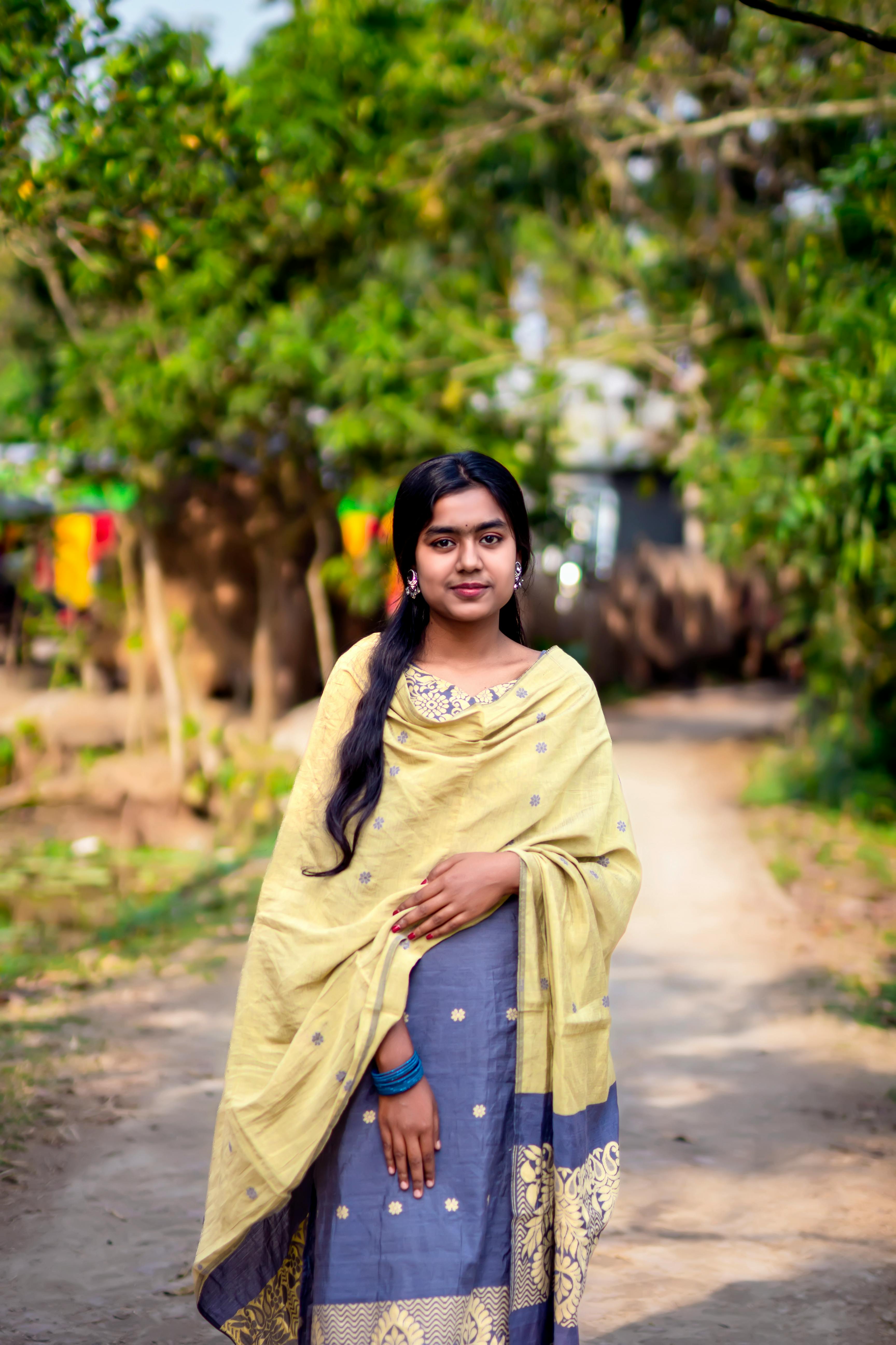 Charming portrait of a young woman in traditional clothing standing outdoors on a sunny day.