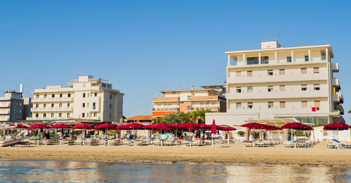 Deslumbrante vista da praia de Lido di Savio com hotéis e guarda-sóis sob um céu de verão claro.