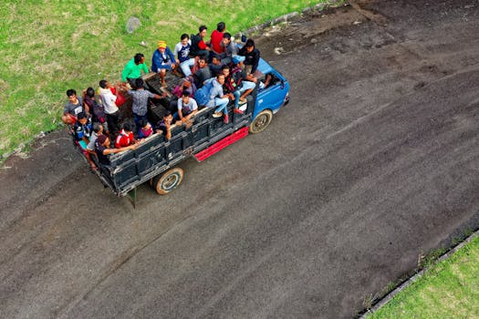 Aerial shot capturing a truck full of people traveling on a rural road in Indonesia.