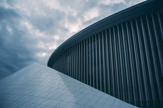 Discover the striking modern architecture of Philharmonie Luxembourg under a dramatic cloudy sky.