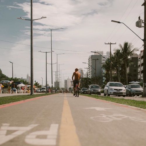 Free Shirtless cyclist riding on a bike lane in urban setting under cloudy skies. Stock Photo