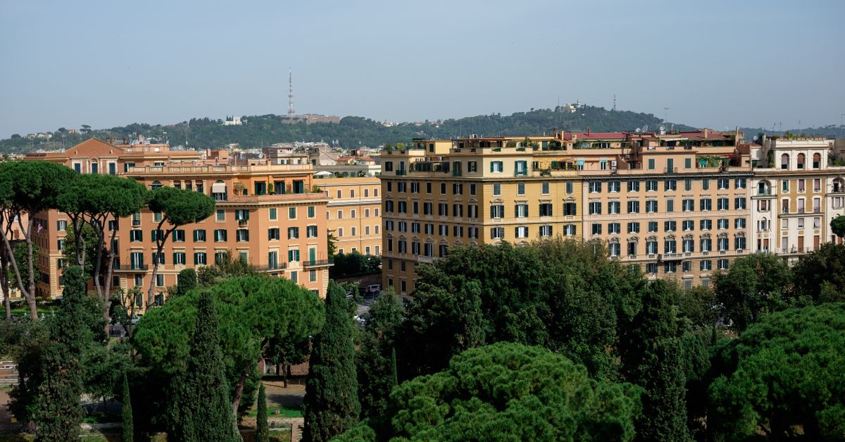 An aerial view of Rome with classic architecture surrounded by lush greenery on a clear day.