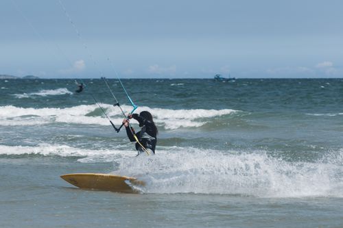 Free Kitesurfer glides through ocean waves on a sunny day, showcasing adventure sport. Stock Photo