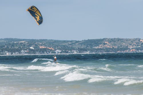 Man Kitesurfing on Waves on Sea Shore