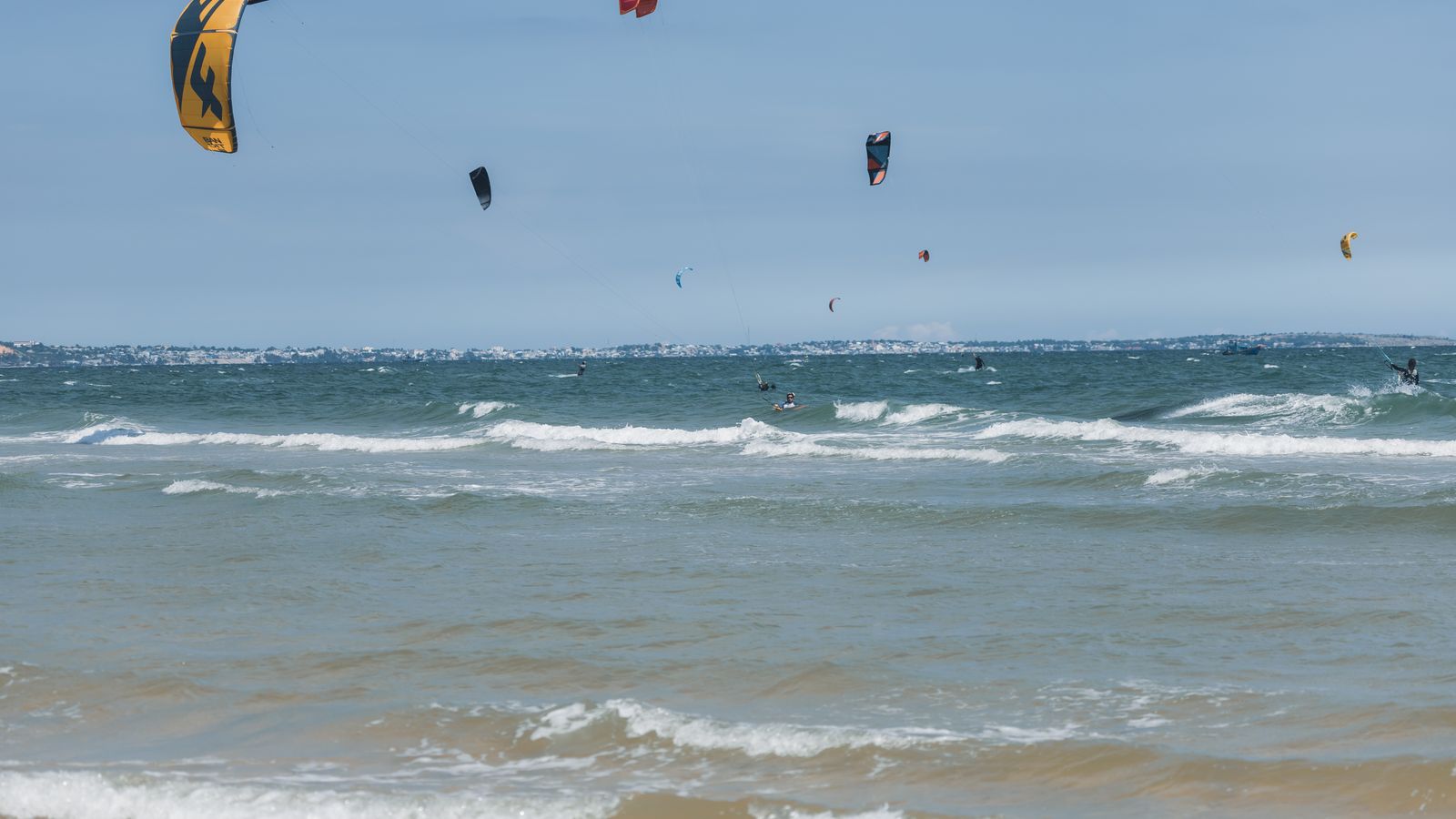 Kites over kitesurfers on sea shore, Senegal