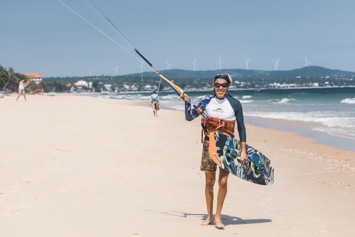 Kitesurfer carrying a board on the beach in Mui Ne