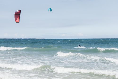 Free Dynamic kitesurfing scene with colorful kites and vibrant ocean waves, perfect for adventure seekers. Stock Photo
