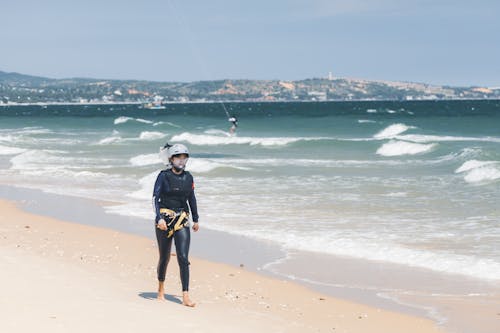 Woman in Swimsuit and Helmet Walking on Beach