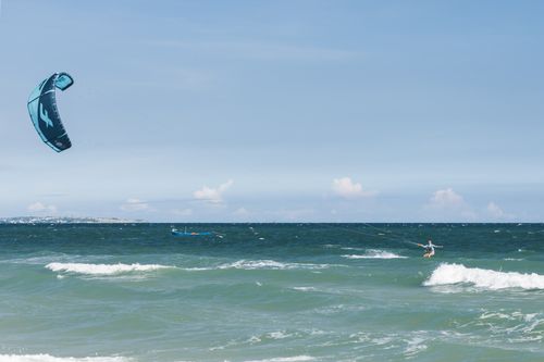Free Exciting kitesurfing experience on ocean with clear skies and rolling waves. Stock Photo