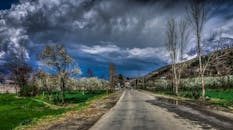 巴基斯坦卡拉姆的乡村道路景色令人惊叹，充满活力的绿色植物与头顶戏剧性的云层交相辉映