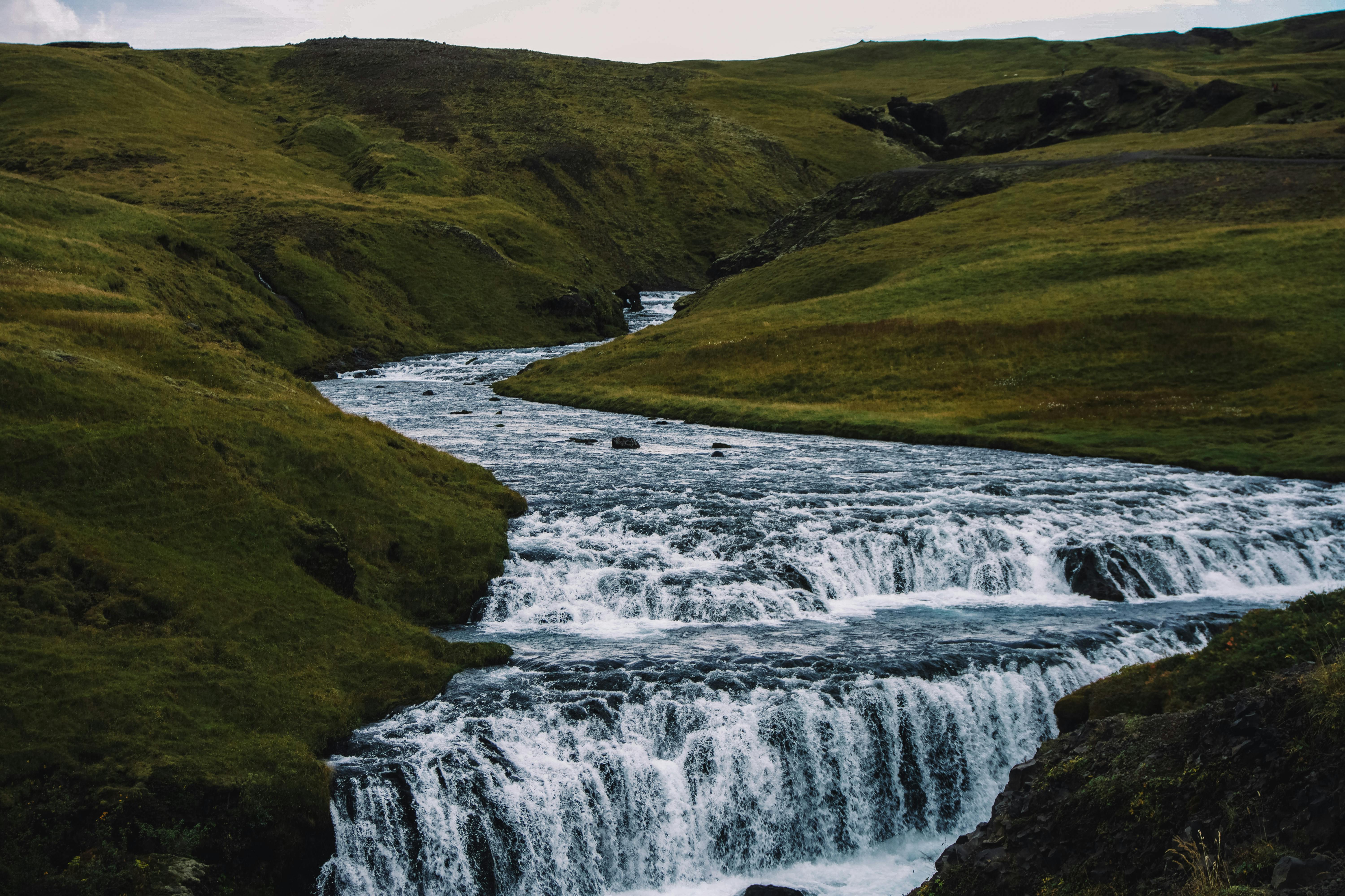 A captivating view of a waterfall cascading through lush Icelandic hills, perfect for nature enthusiasts.