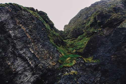 Free A striking rocky cliff with lush green patches, showcasing raw natural beauty. Stock Photo