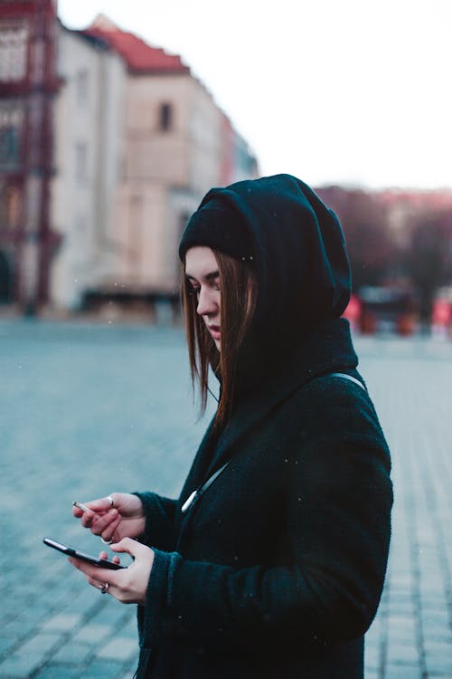 Free Woman Wearing Hoodie While Using Smartphone Stock Photo