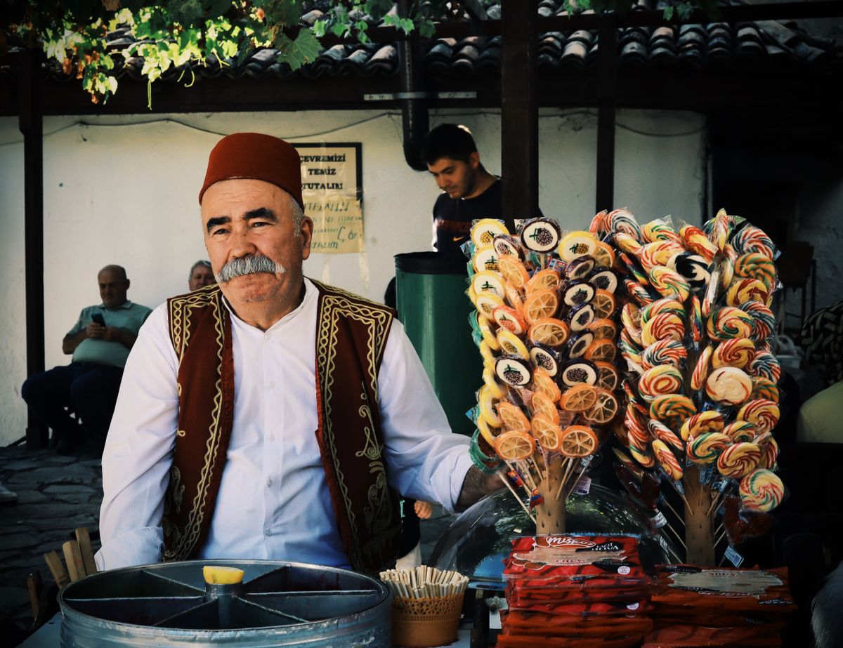 Traditional Turkish merchant in Safranbolu selling colorful lollipops outdoors.