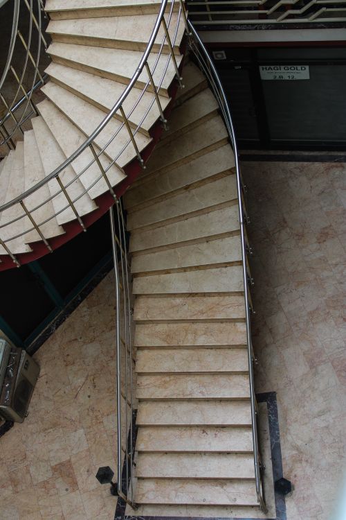Free Aerial view of a modern spiral staircase indoors with metal handrails. Stock Photo