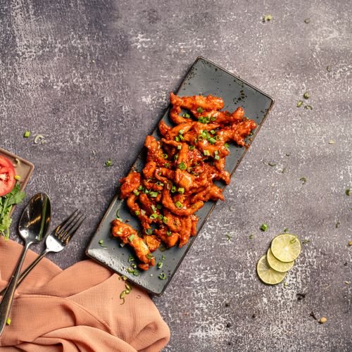 Free A mouth-watering platter of spicy chicken garnished with spring onions, perfect for a tasty meal. Stock Photo