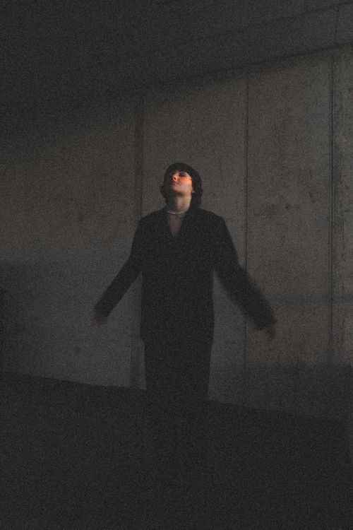 Free A person in a black jacket looks up in a dimly lit urban tunnel, exuding a moody vibe. Stock Photo
