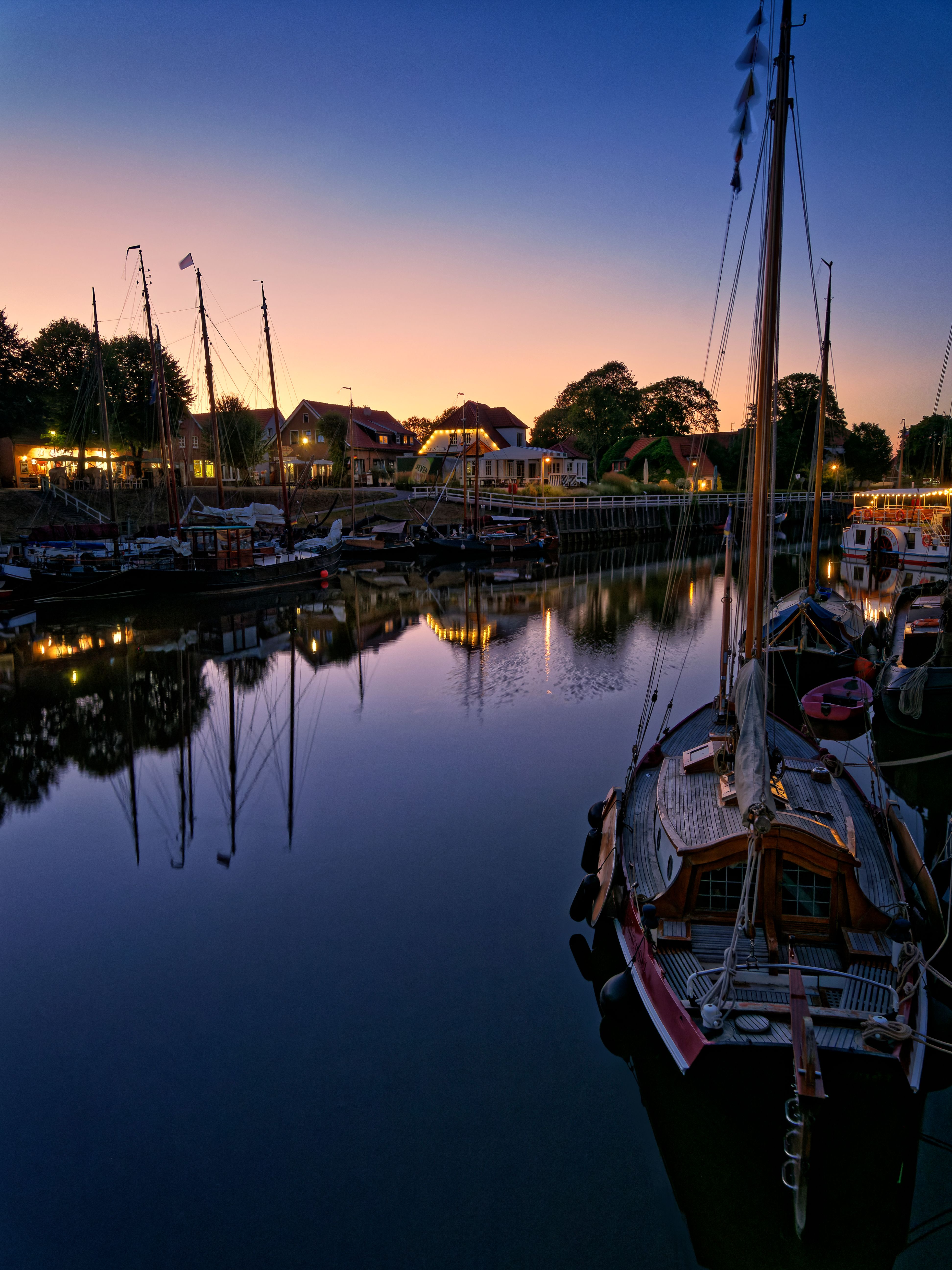 Beautiful canal scene with illuminated boats and reflections at sunset, capturing a serene urban waterfront.