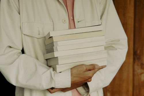 Free Close-up of an adult holding a stack of books, emphasizing education and knowledge. Stock Photo