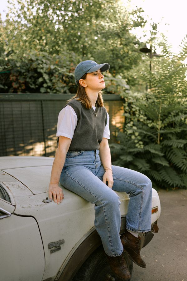 woman in argyle sweater vest over white button-down with jeans and booties