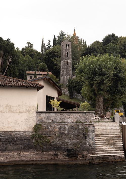 Free Scenic view of a medieval village showcasing a stone tower and lush greenery by the riverside. Stock Photo