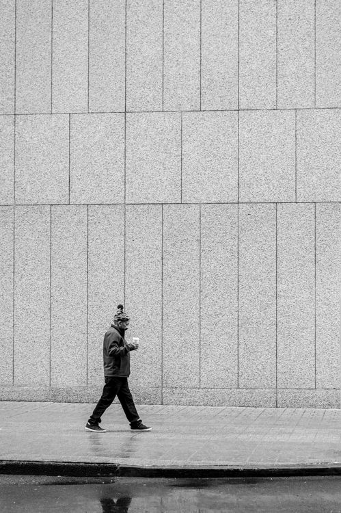 Man Walking on Sidewalk by Building Wall in Black and White · Free