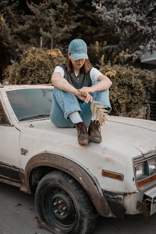 Woman in a Casual Outfit Sitting on a Car Hood 