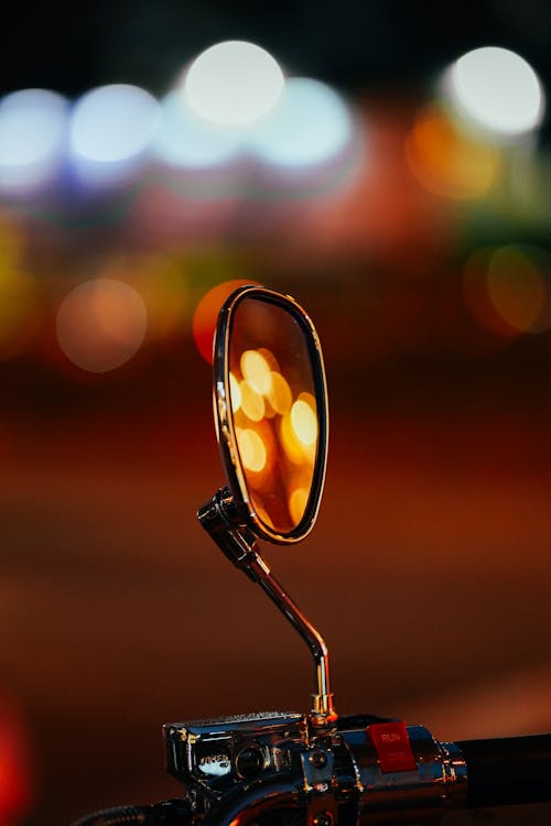 Close-up of a Motorcycle Mirror Reflecting Blurry Lights 