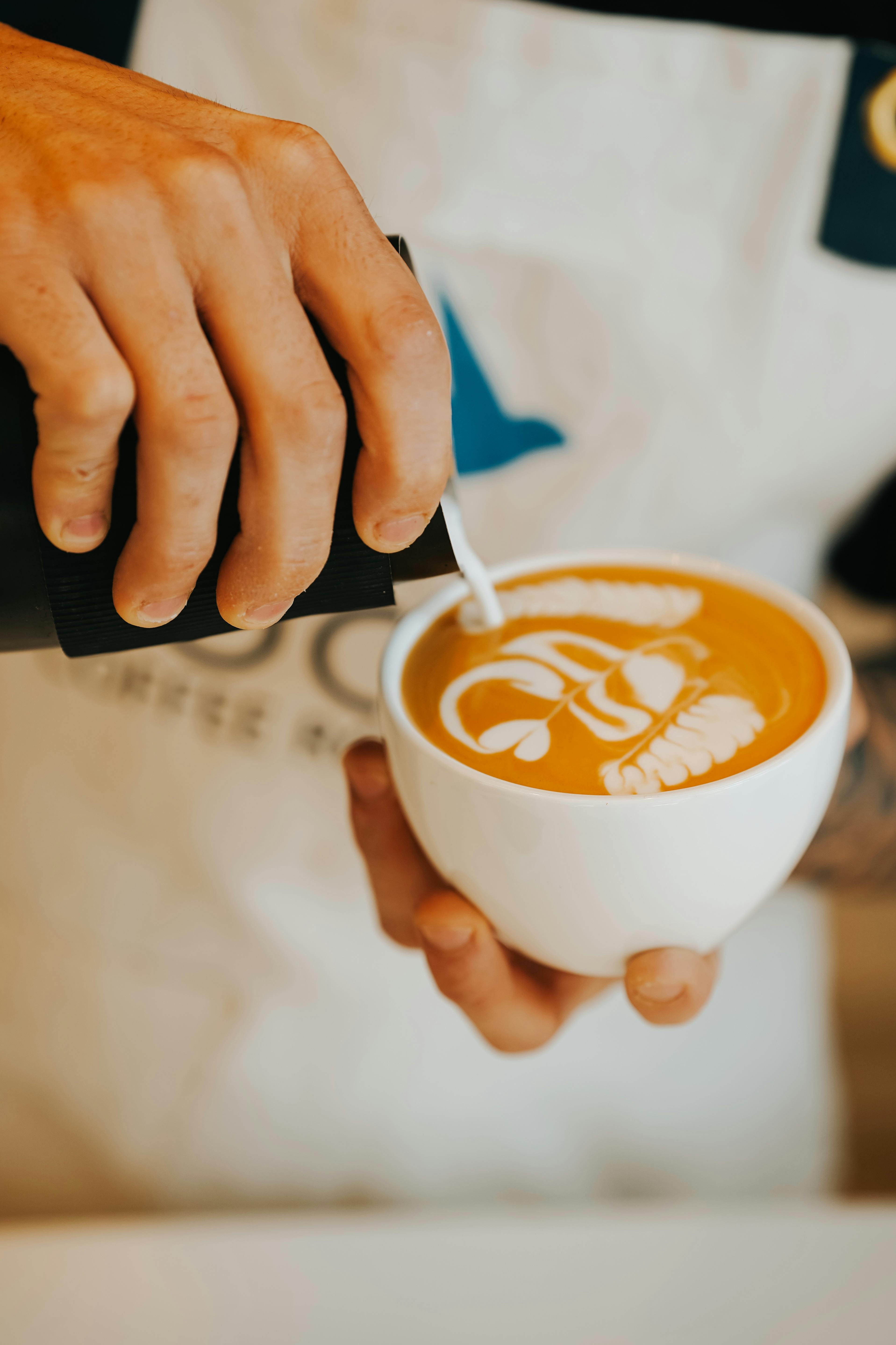 Barista skillfully pouring milk to create intricate latte art in a cafe in Ankara, Türkiye.