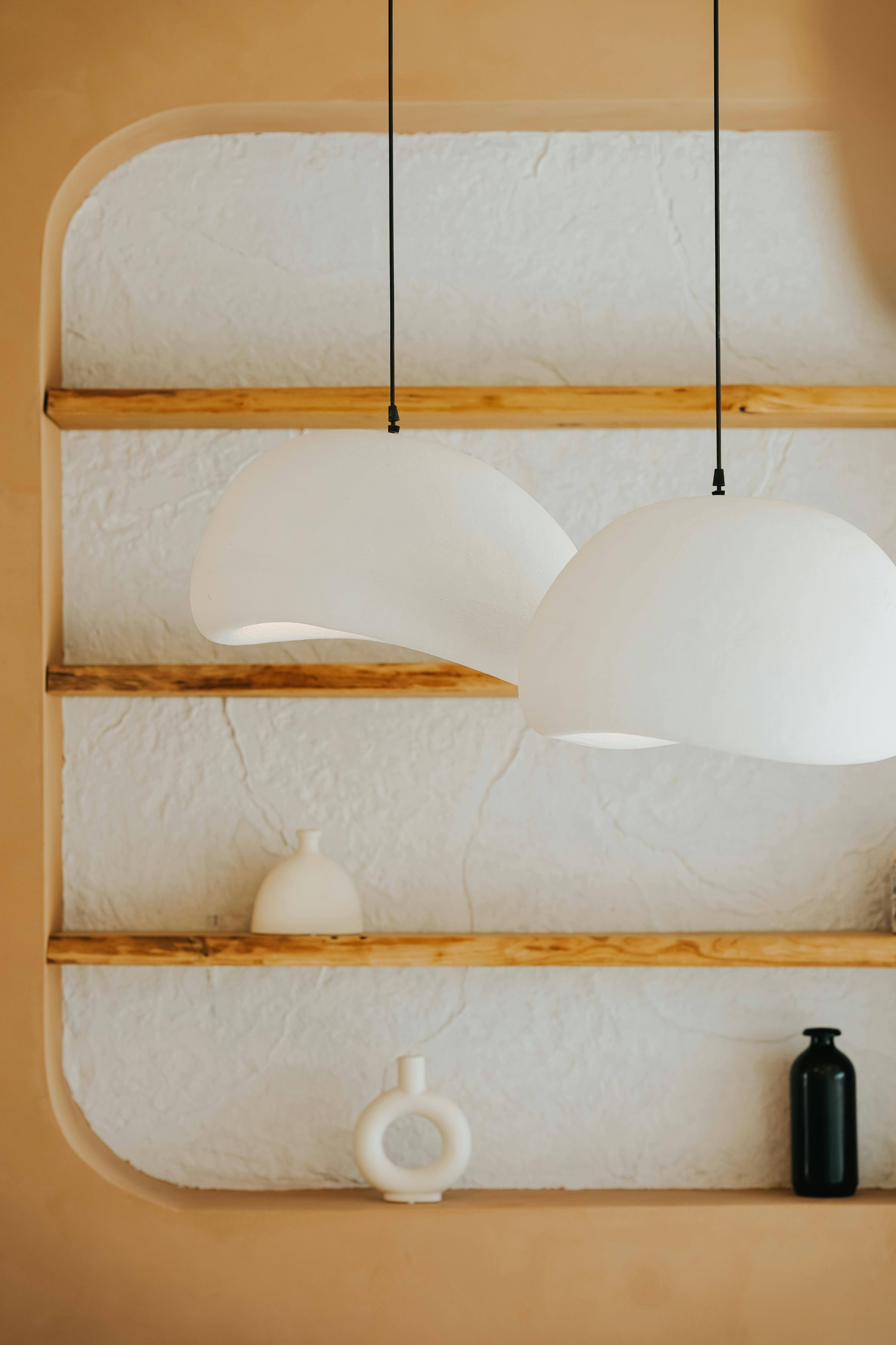 Pendant lamps and open shelving in a lived-in room, showing how lighting has to sit gently among other objects.