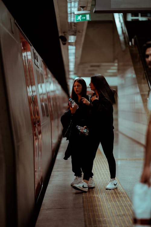 Two Young Women Walking on a Subway Station Platform 