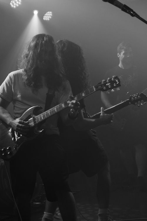 Free Energetic concert scene with musicians playing guitars under dramatic lighting. Stock Photo