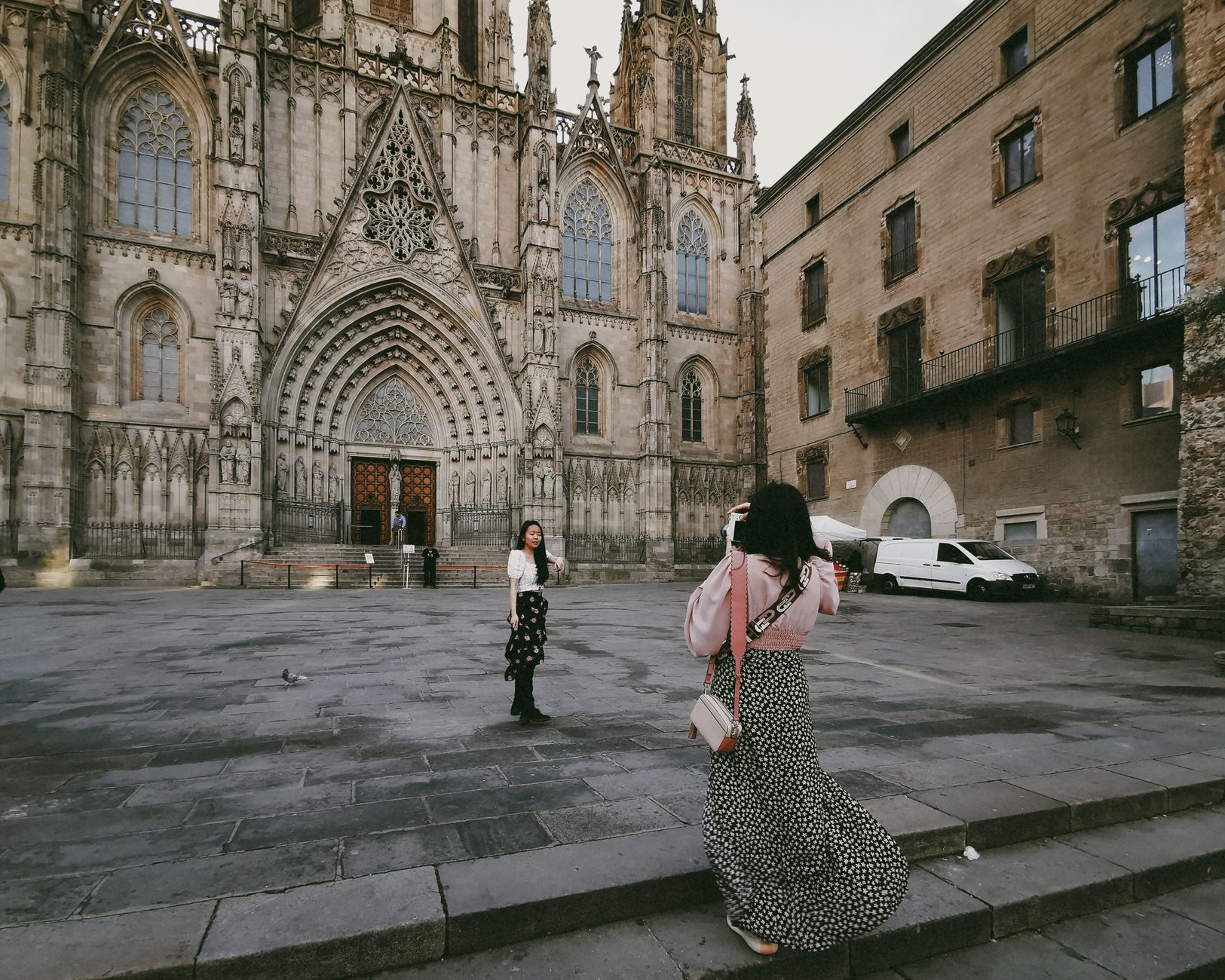 Two women capture the Gothic facade of Barcelona Cathedral, a landmark of Christian heritage in Spain.