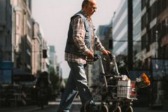 An elderly man crossing a Berlin street with a walker and groceries, underlining urban life and independence.