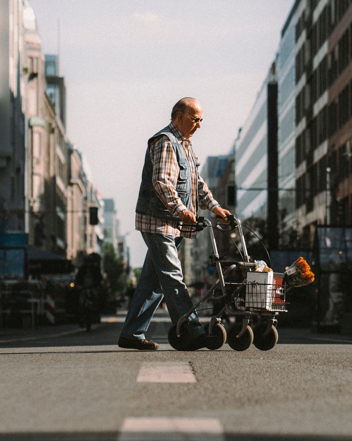 Hombre mayor caminando por la calle con su andador y la compra, recuperada la autonomía tras una fractura