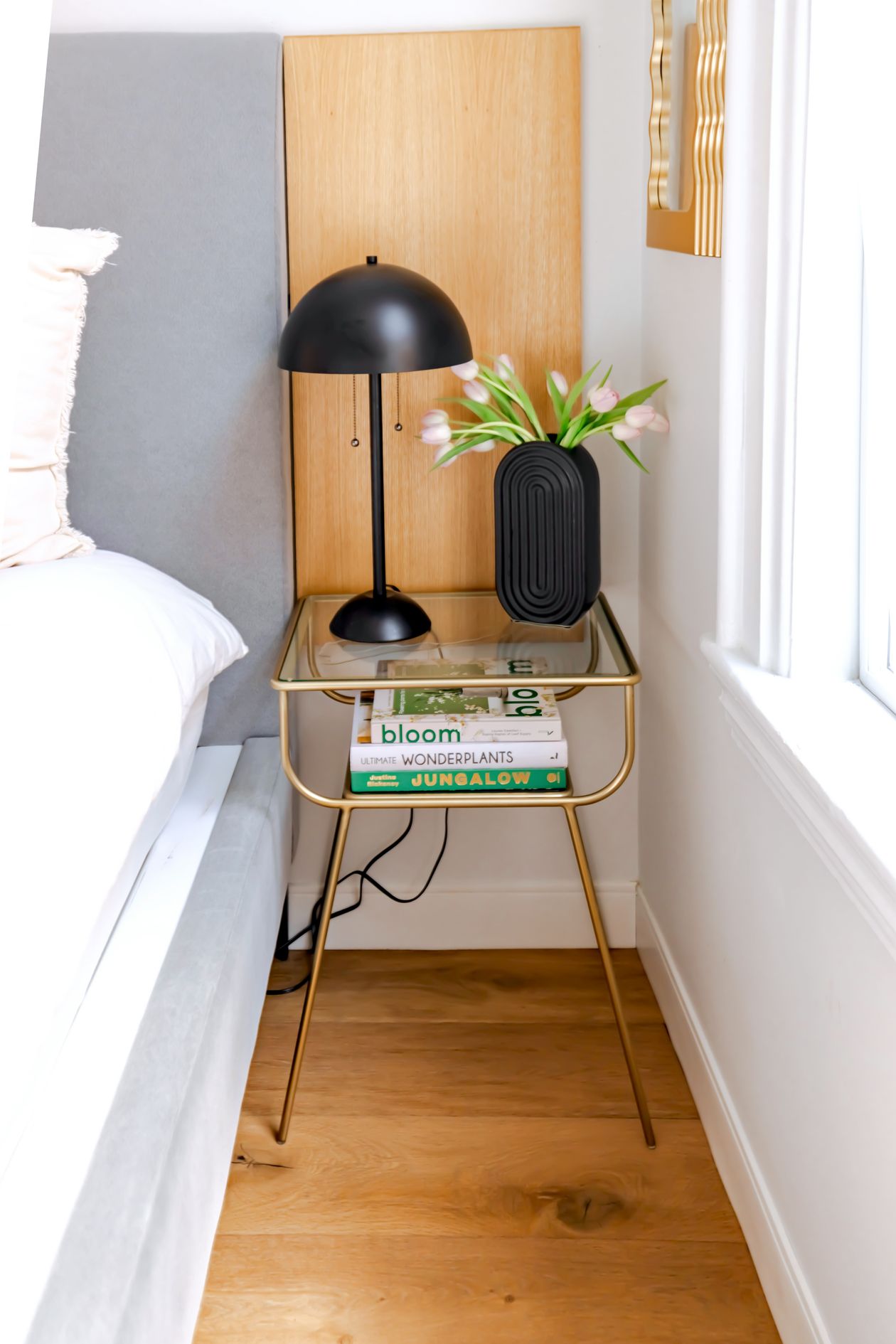 how to style a nightstand: a nightstand with a lamp, books, and flowers
