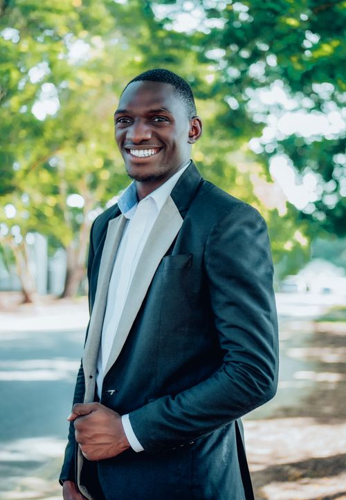Free Smiling man in a stylish tuxedo under summer sunlight, exuding elegance. Stock Photo