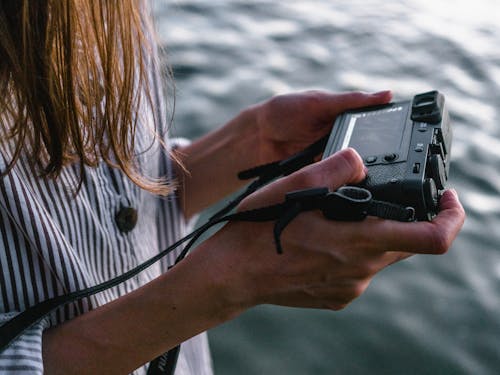 Free Close-up Photo of Woman Viewing Photos from Her Camera Near Body of Water Stock Photo