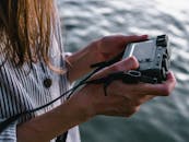 一个女人拿着相机在水边，捕捉户外的宁静时刻