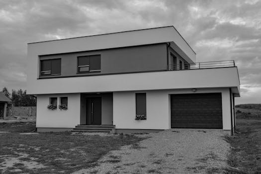 Grayscale photo of a modern two-story house with a garage, showcasing contemporary architecture.