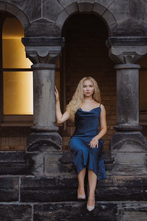 Blonde Model in Blue Dress Sitting between Columns