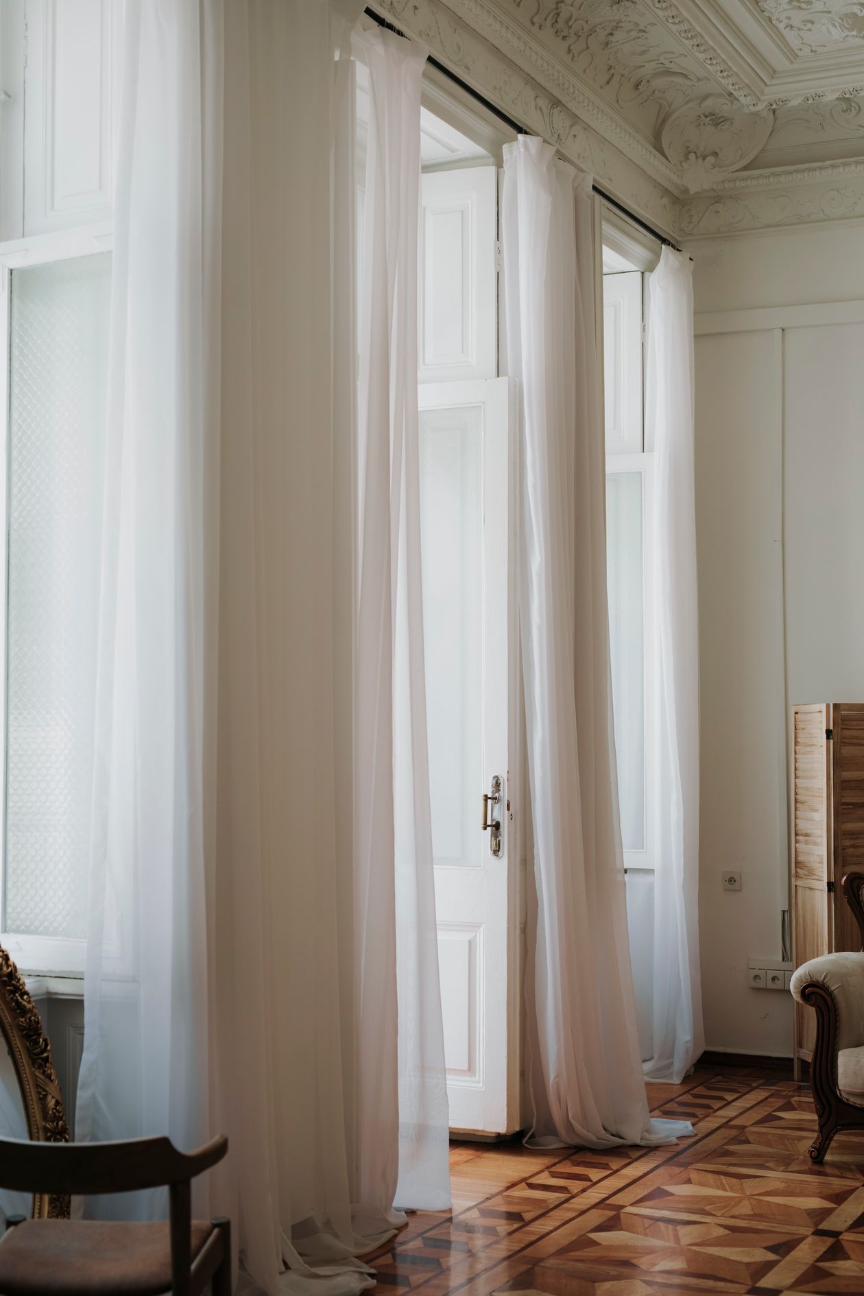 Tall white curtains hanging in a bright elegant room