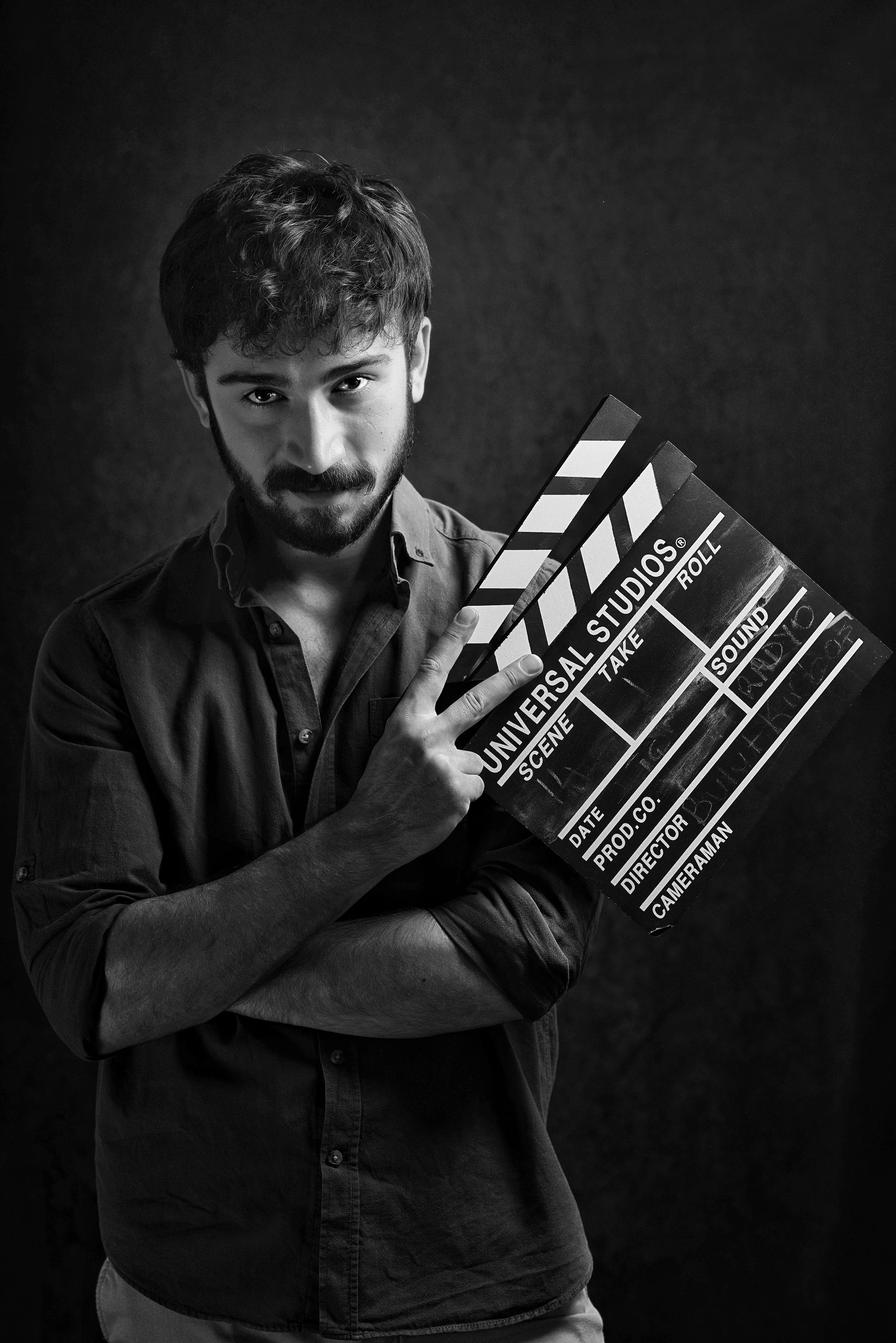 Bearded filmmaker holding a clapboard in dramatic black and white