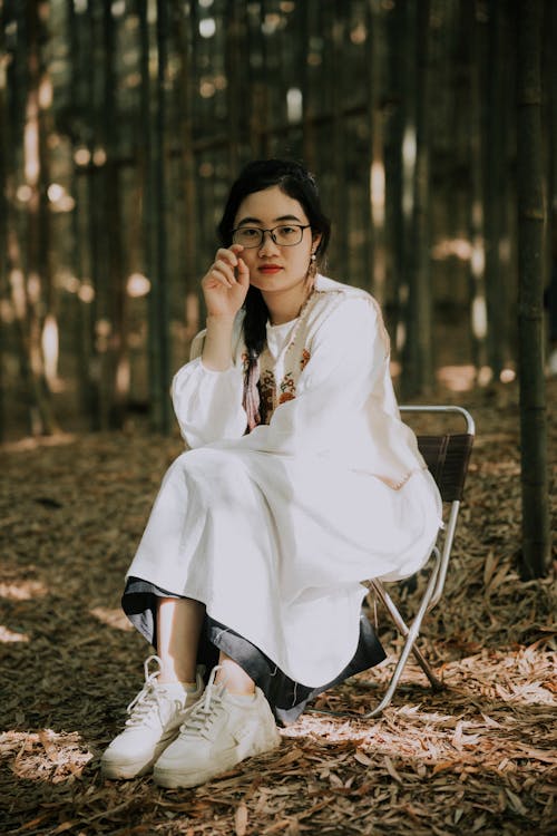 Woman in Traditional Dress Sitting in Bamboo Forest