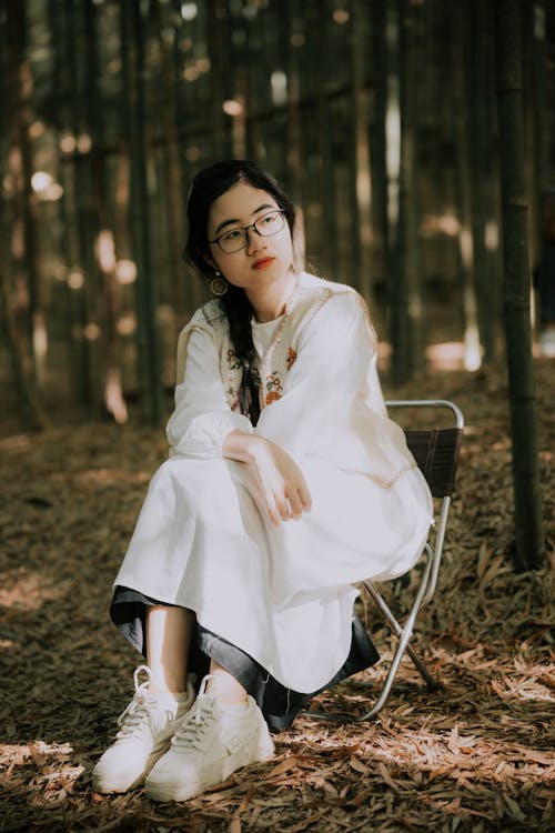Woman in White, Traditional Dress Sitting in Forest