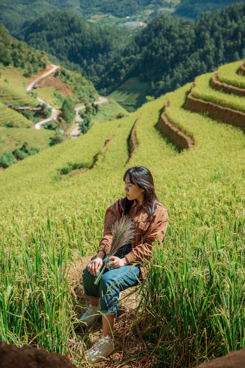 Woman in Jacket Sitting on Chair on Rural Field in Countryside and Holding Grain