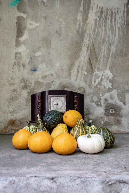 Pile of Ornamental Pumpkins in Front of an Antique Clock