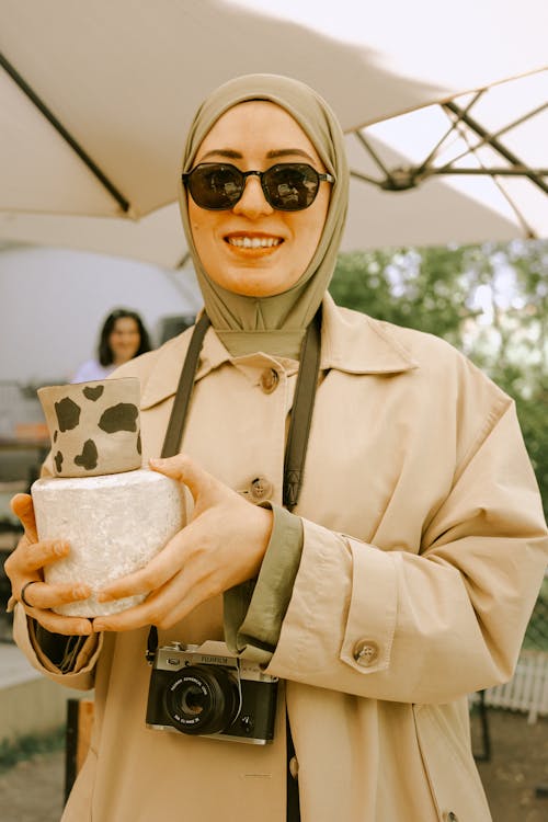 Smiling Woman in Hijab and Coat Holding Clay Bowl and Cup